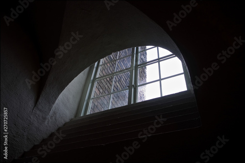 view from a dark room through a graphic semi-circular old window