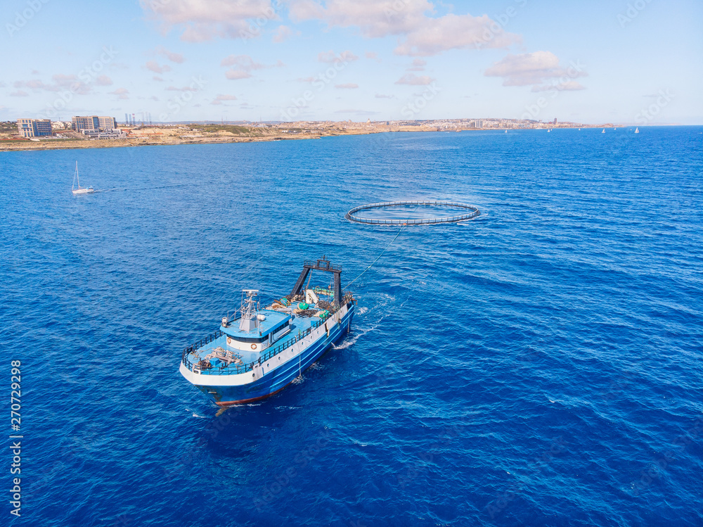 Transportation of fish in cage to farm and port market. Blue sea background. Aerial top view Transportation of fish in cage to farm and port market. Blue sea background. Aerial top view