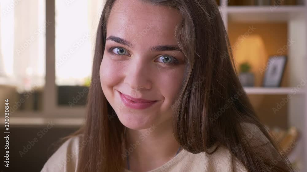 Closeup portrait of young attractive caucasian female smiling happily looking at camera indoors in apartment Closeup portrait of young attractive caucasian female smiling happily looking at camera indoors in apartment