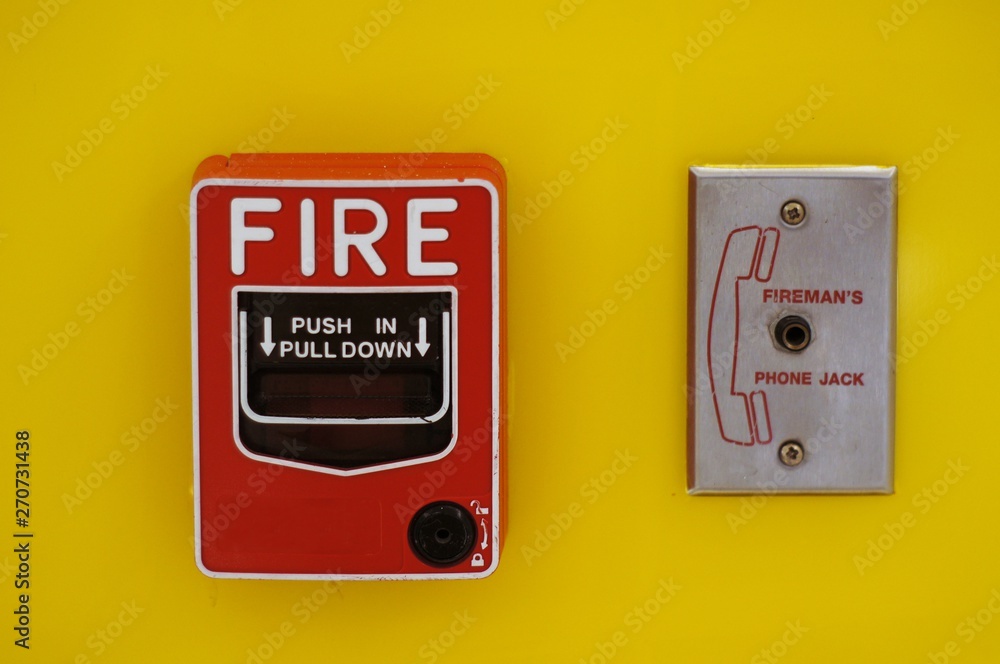 Red Fire alarm pull station Switch install on bright yellow wall Red Fire alarm pull station Switch install on bright yellow wall
