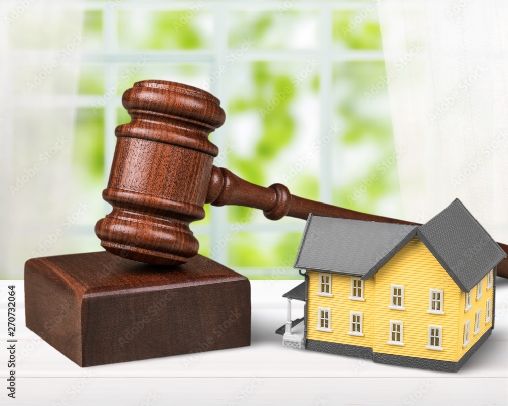 Wooden judge gavel and toy house on background Wooden judge gavel and toy house on background