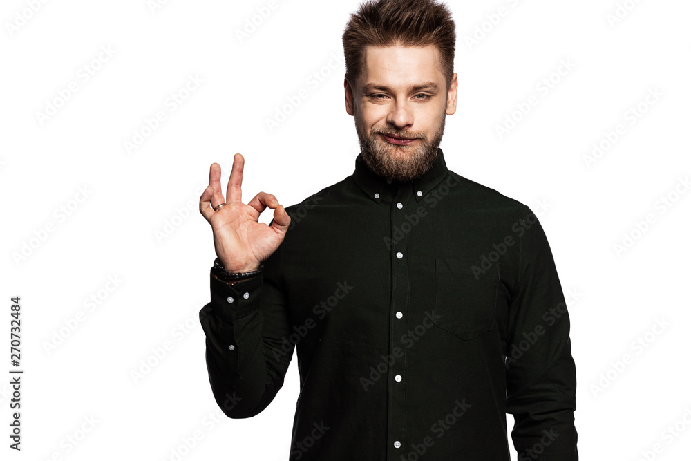Portrait of smiling confident man showing okay sign. Well-dressed male in black standing indoors. Brunette person with perfect beard. Happiness and positivity concept. Isolated on white Portrait of smiling confident man showing okay sign. Well-dressed male in black standing indoors. Brunette person with perfect beard. Happiness and positivity concept. Isolated on white