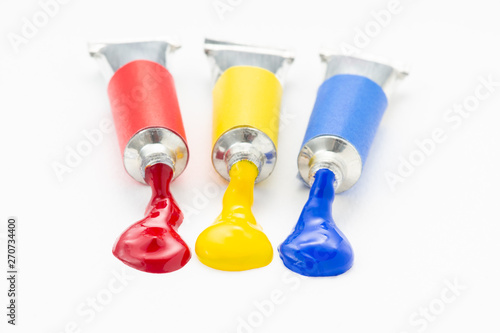 Three of the primary colour flow out of the tube on rough white paper