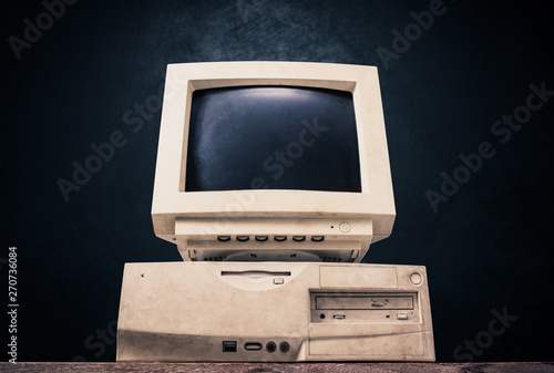 Front side of old and obsolete computer on old wood table with dark background