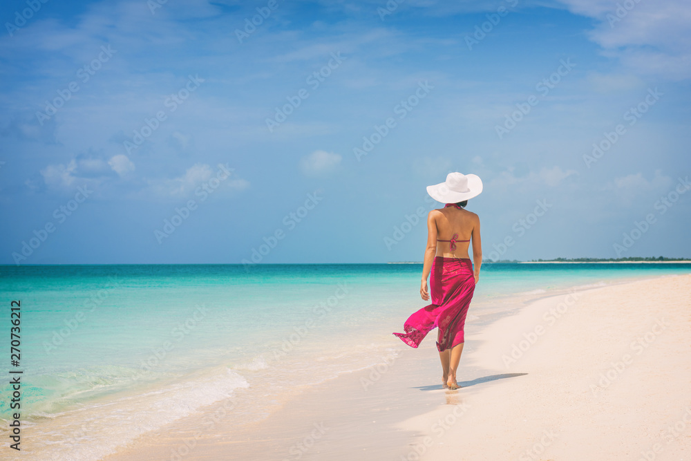 Luxury travel vacation elegant lady walking on beach in pink fashion skirt wrap relaxing on Caribbean holidays during winter. Luxury travel vacation elegant lady walking on beach in pink fashion skirt wrap relaxing on Caribbean holidays during winter.