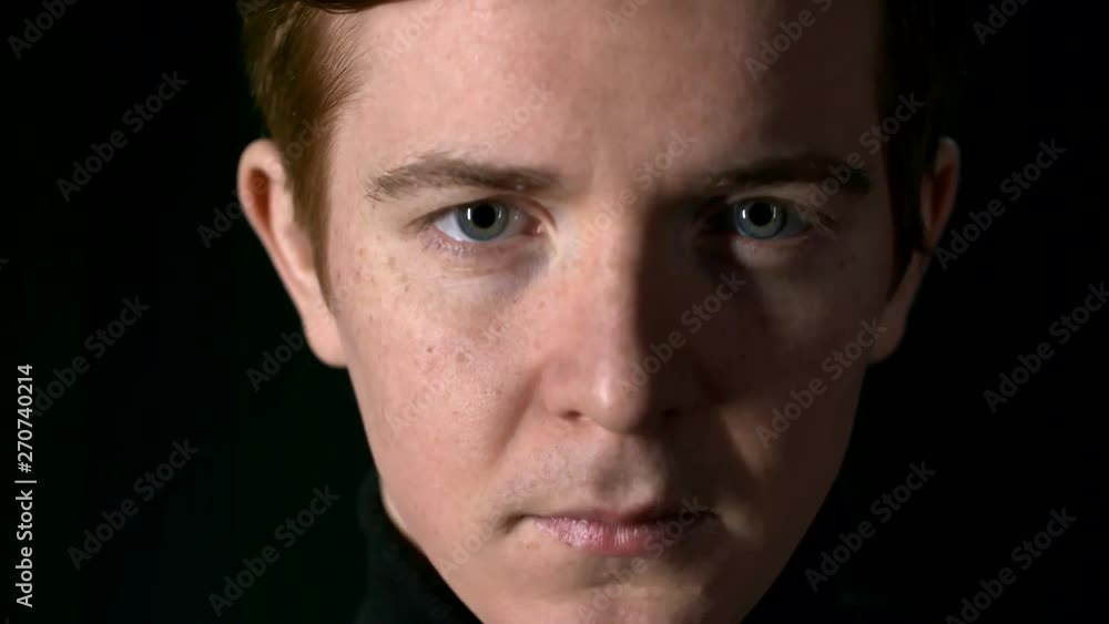 Close up of face of young Caucasian man turning up and looking at camera on black background Close up of face of young Caucasian man turning up and looking at camera on black background