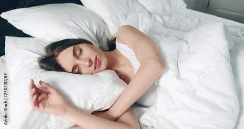 Pretty young sleeping woman in the morning bed