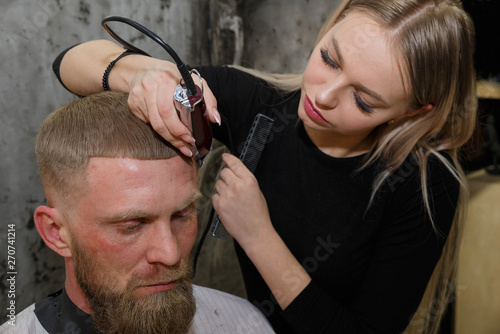 Hairdresser cuts machine man closeup in a barbershop.