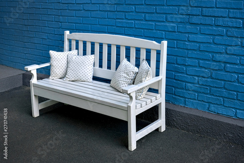 white wooden bench with pillows on blue brick wall background photo