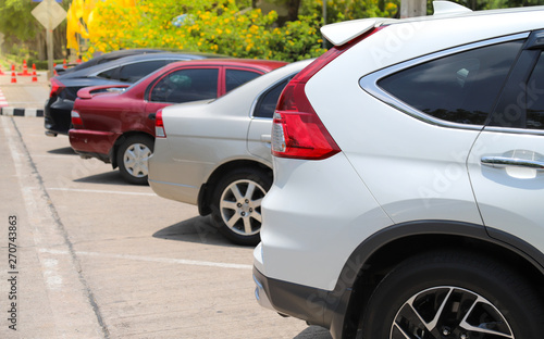 Closeup of rear, back side of white car with other cars parking in outdoor parking lot beside the street. © Amphon