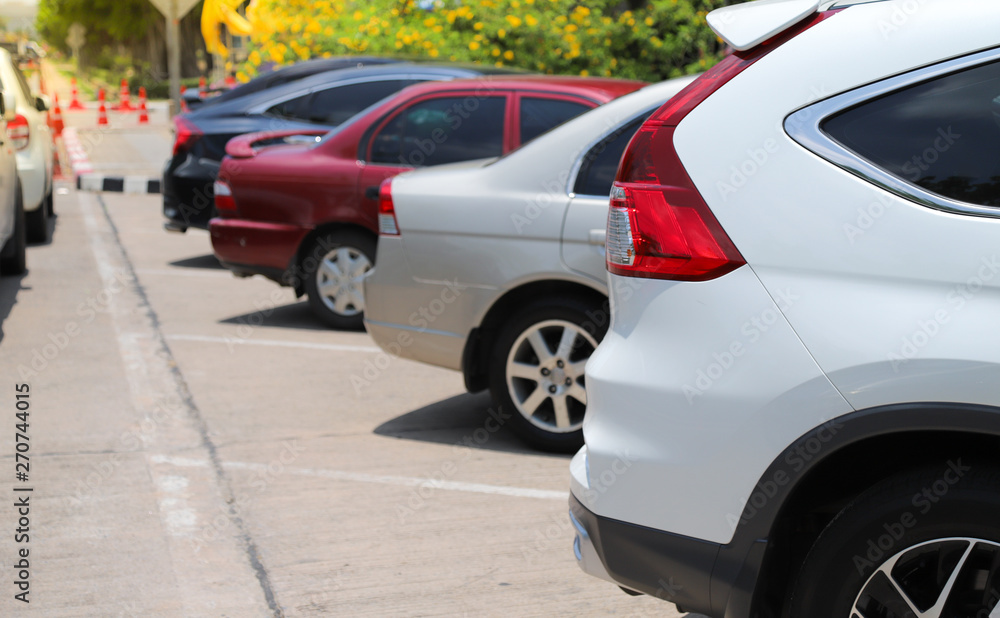 Closeup of rear side of white car with other cars parking in outdoor parking lot beside the street with natural background in bright sunny day. Closeup of rear side of white car with other cars parking in outdoor parking lot beside the street with natural background in bright sunny day.