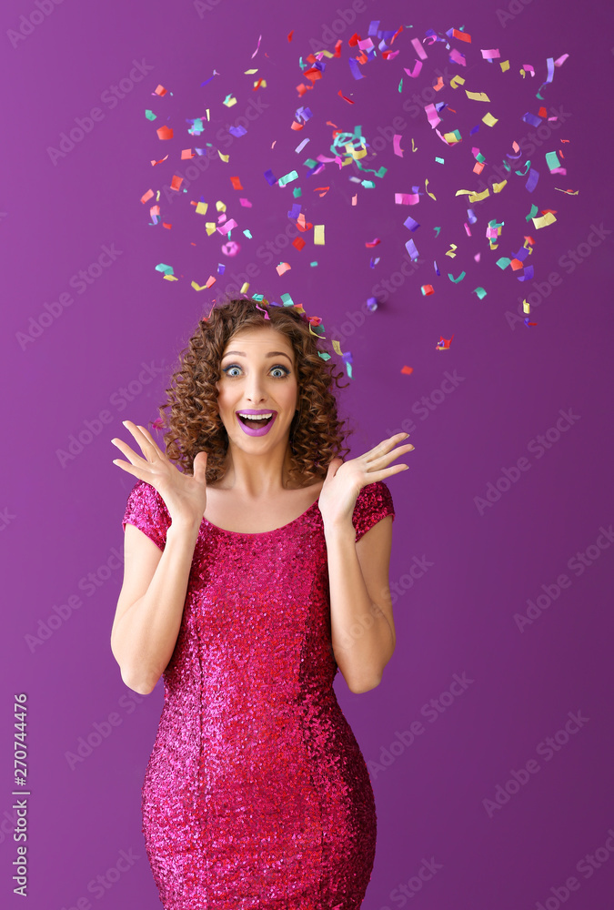 Surprised young woman with confetti on color background Surprised young woman with confetti on color background