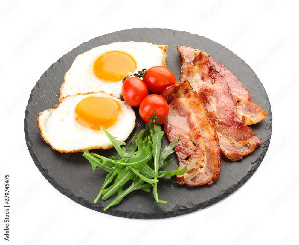 Slate plate with fried eggs, bacon and tomato on white background Slate plate with fried eggs, bacon and tomato on white background