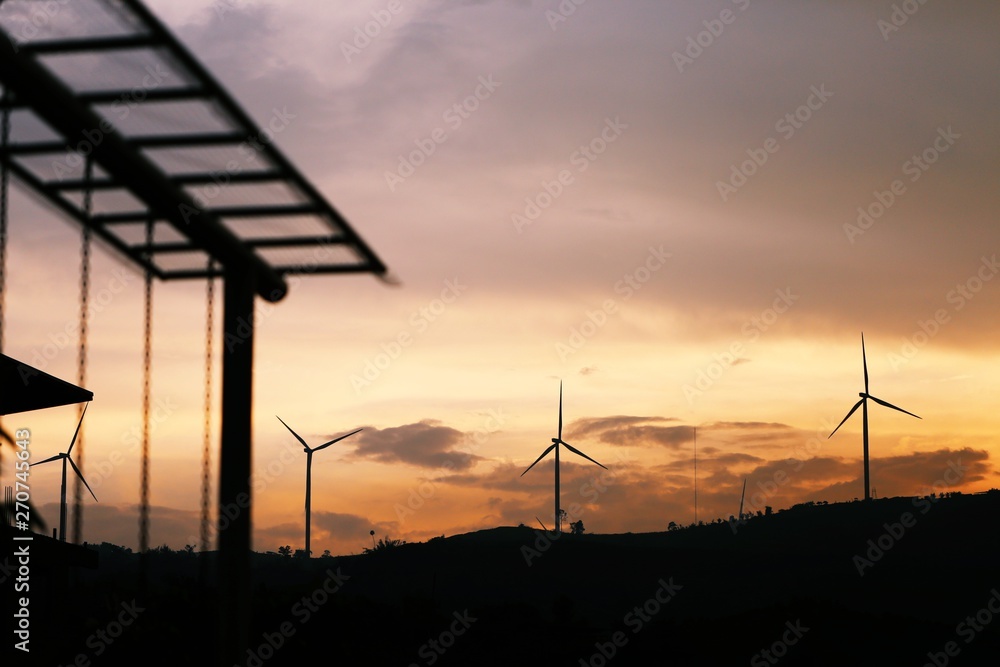 Obraz premium Silhouette of wind turbines at sunset