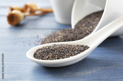 Fotografía Spoon with poppy seeds on wooden table, closeup