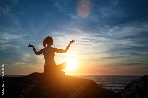 Yoga silhouette young woman on the Sea beach at beautiful sunset.