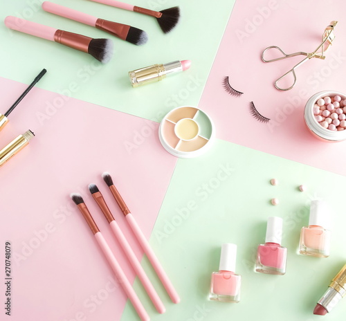 Makeup products, decorative cosmetics on pastel color pink mint background flat lay. Fashion and beauty concept. Top view. Copy space.