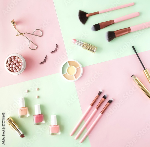 Makeup products, decorative cosmetics on pastel color pink mint background flat lay. Fashion and beauty concept. Top view. Copy space.