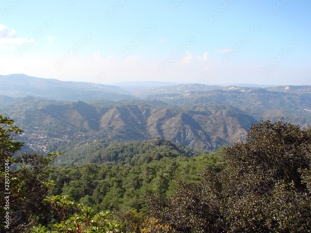 A panorama from the height of the mountain is a barely cloudy blue sky that stretches to the horizon over endless mountain ranges covered with forest.