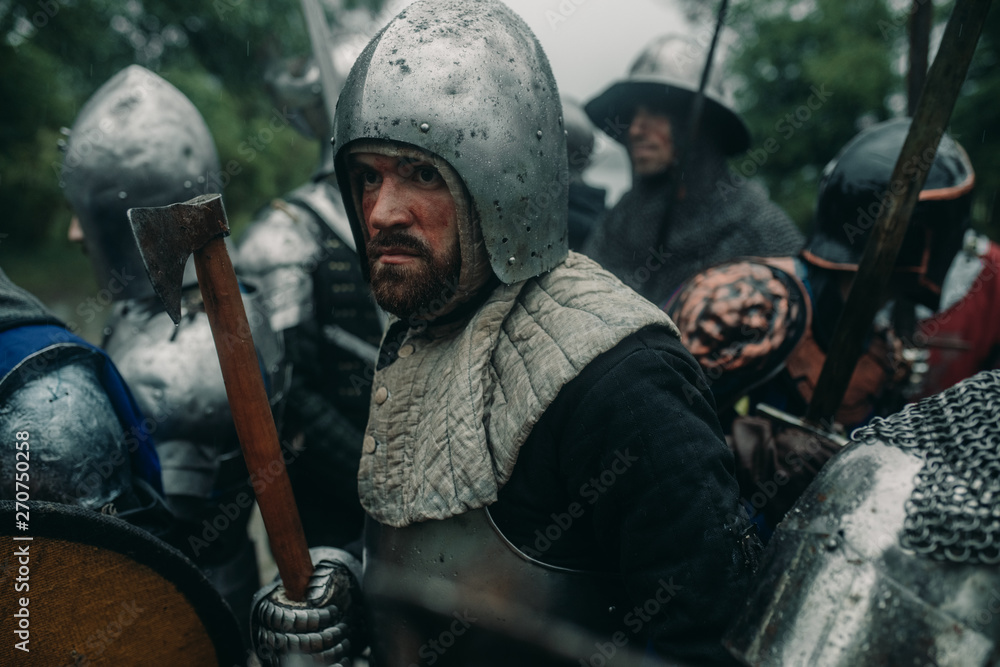 Squad of medieval knights of the Crusaders stand in armors with their weapons. Squad of medieval knights of the Crusaders stand in armors with their weapons.