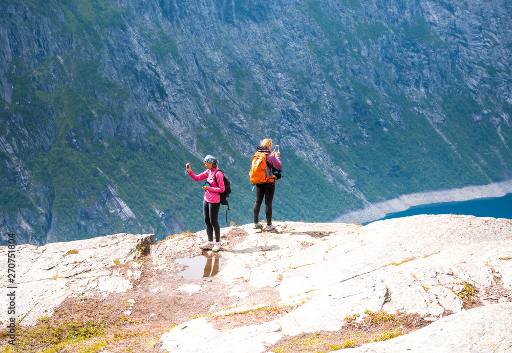 Fototapeta premium Two sporty women on the edge of Norway fjord making photo