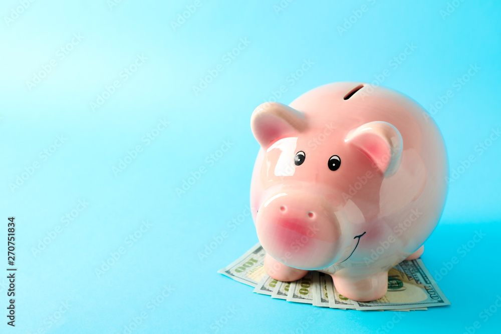 Happy piggy bank with dollars on color background, space for text. Finance, saving money