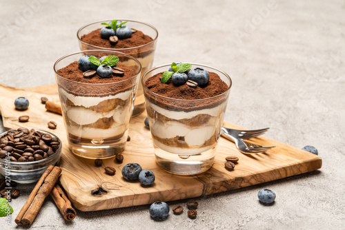 Classic tiramisu dessert in a glass with blueberries on concrete background photo