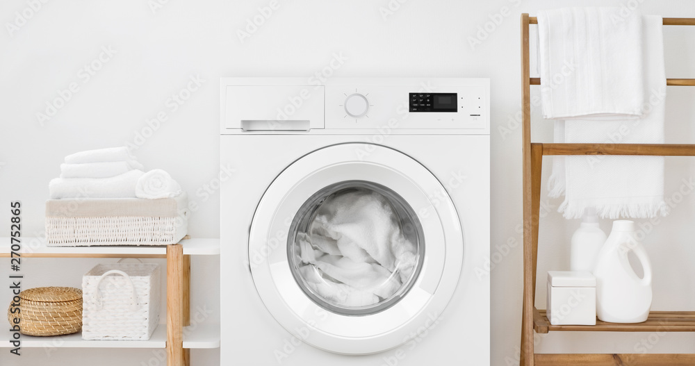 Washing machine with laundry and shelves on white wall background Washing machine with laundry and shelves on white wall background