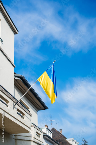 Flag of Ukraine on a diplomatic representation building with clear blue sky in background