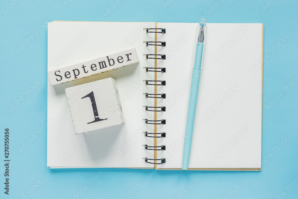 September 1 on a wooden calendar on study textbook on blue background. Back to school concept September 1 on a wooden calendar on study textbook on blue background. Back to school concept
