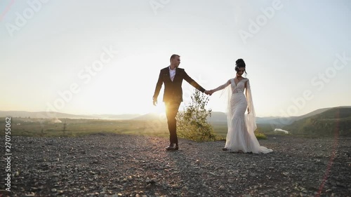 Wallpaper Mural The bride and groom hold hands and walk along the mountains rock on the sunset. Torontodigital.ca