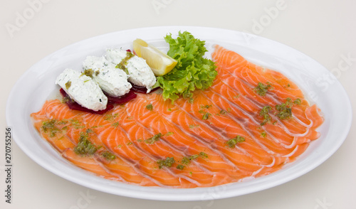 Red fish sliced on white plate, restaurant table setting, cheese paste, lemon, white background