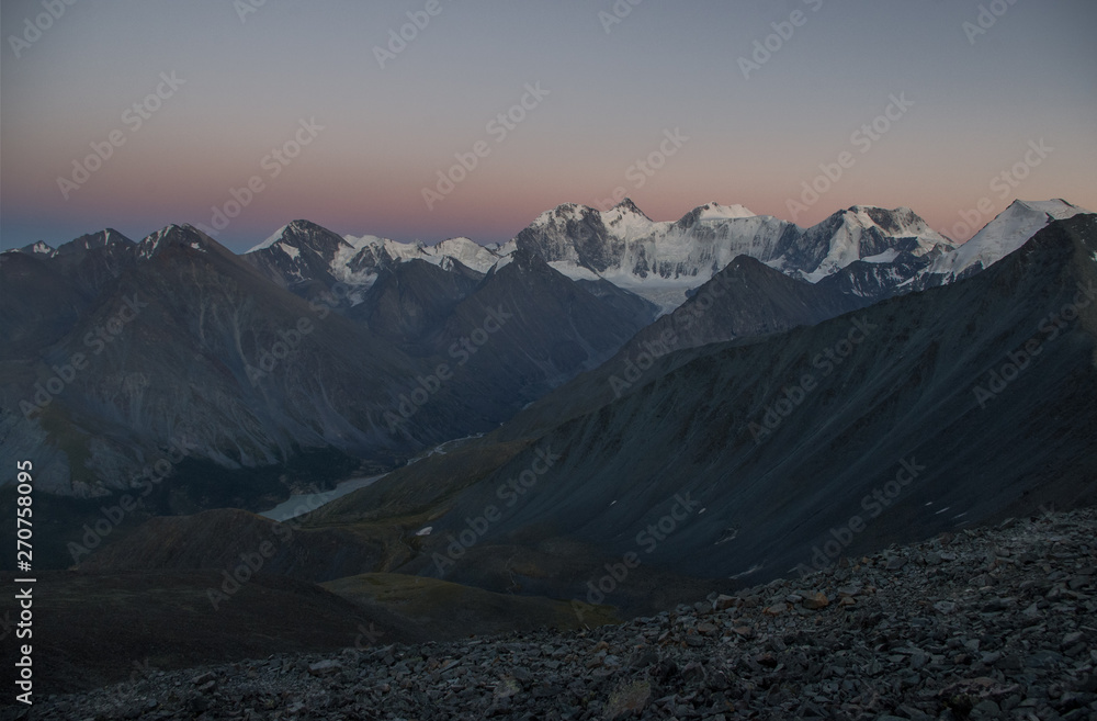 Dark desert night mountain valley with ranges of  snow peaks on a horizon in a twilight
