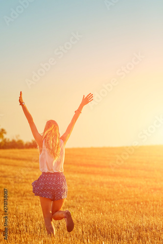 Young woman jumping and running in a wheat field. © astrosystem