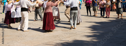 Amateur Folk Group in Round Dance is on Sunny Street. Viewers are Enjoying Happy Atmosphere. Horizontal Background with Copy Space. Concept: Summer Holidays and Festivals Around the World. 