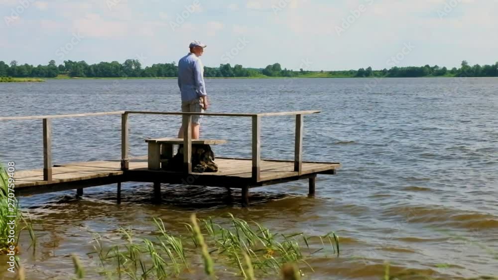man walks and stands on pier at the lake in windy weather man walks and stands on pier at the lake in windy weather