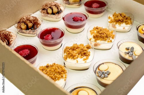 Collection of take away kraft boxes with different desserts on white background, top view.