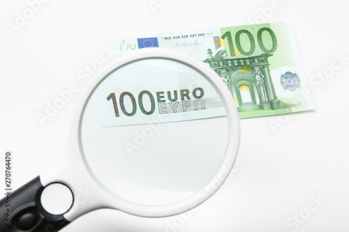 100 Euro banknote on white background under magnifying glass. number 100 euro in the loupe.