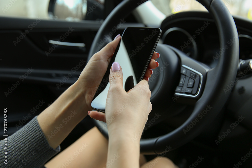 women's hands holding the phone in the car. using the phone while driving. a woman with a phone sitting behind the wheel of a car. search of a road by navigator of the smartphone