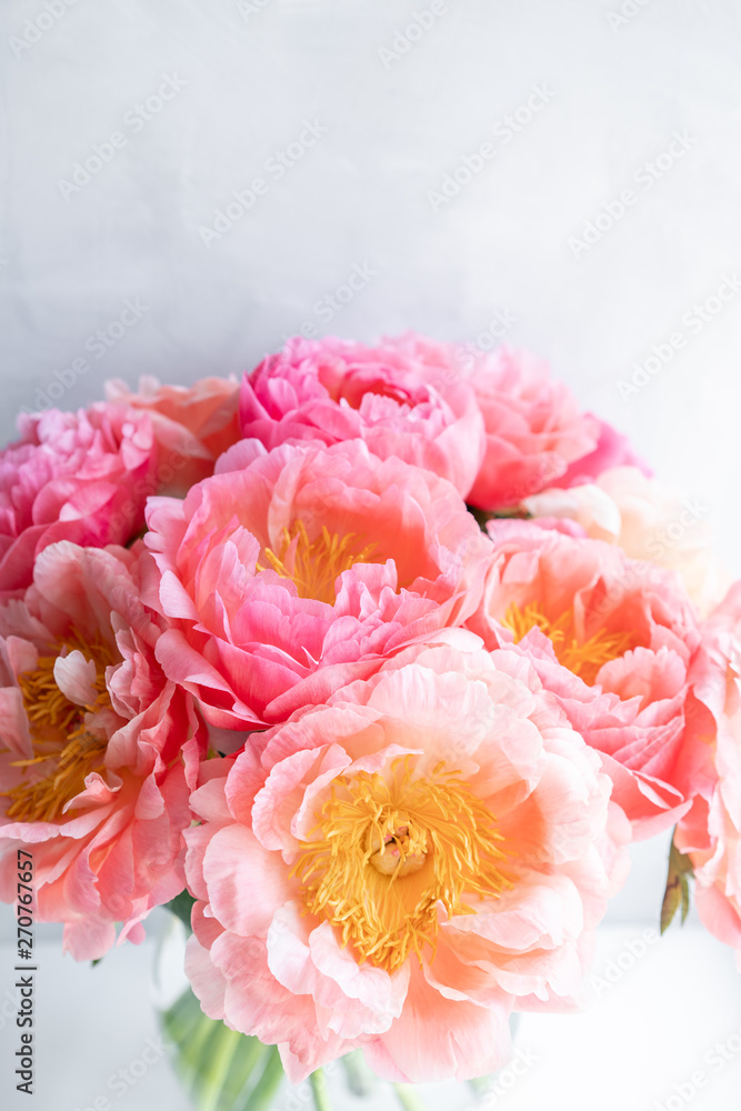 Coral peonies. Flowers in a vase on a white windowsill. Morning light in the room. Beautiful peony flower for catalog or online store. Floral shop and delivery concept .