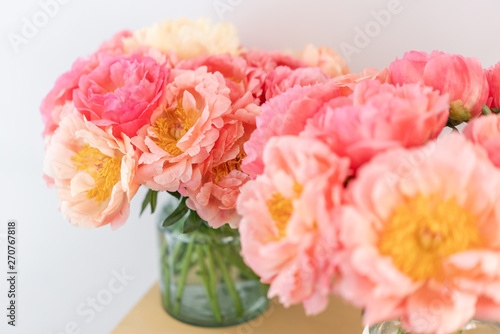 Focus on the background. Cozy and atmosphere at home. Two glass vases with Coral peonies. Morning light in the room. Beautiful peony flower for catalog or online store.