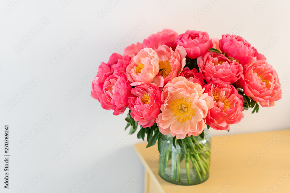 Coral peonies in a glass vase on wooden table.. Beautiful peony flower for catalog or online store. Floral shop concept . Beautiful fresh cut bouquet. Flowers delivery. Copy space Coral peonies in a glass vase on wooden table.. Beautiful peony flower for catalog or online store. Floral shop concept . Beautiful fresh cut bouquet. Flowers delivery. Copy space