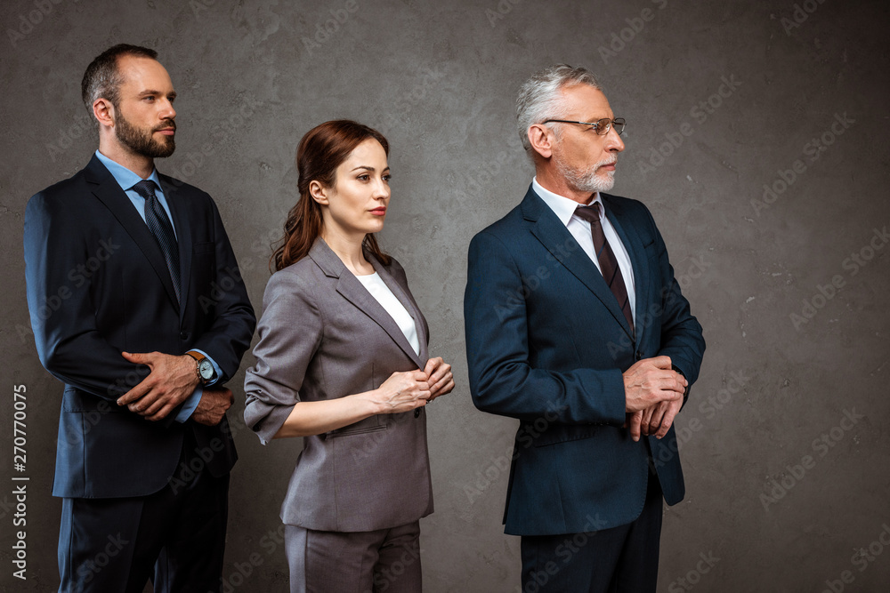 businessmen and attractive businesswoman standing in formal wear on grey businessmen and attractive businesswoman standing in formal wear on grey