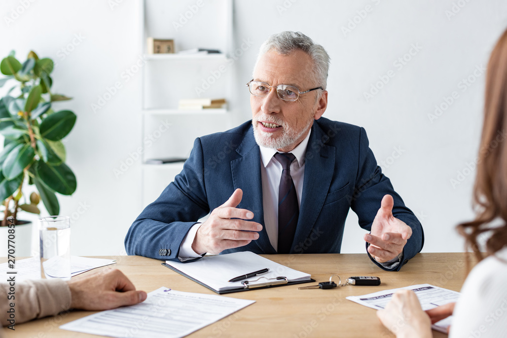 selective focus of car dealer gesturing while talking with customers selective focus of car dealer gesturing while talking with customers