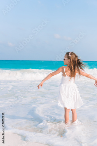 Active little girl at beach having a lot of fun on the shore making a leap