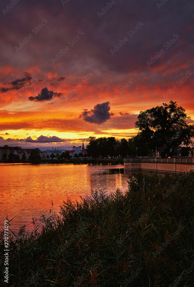 Reed edge with sunset and dramatic clouds over the Schwerin old town. Mecklenburg-Vorpommern, Pomerania, Germany