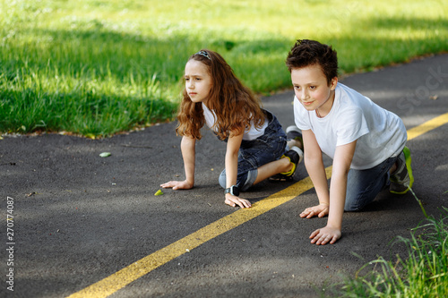 Picture of brother and sister prepare for run in the summer park on sunset. Cheerful children. Little girl and boy playing outdoors, best friends. Childhood concept