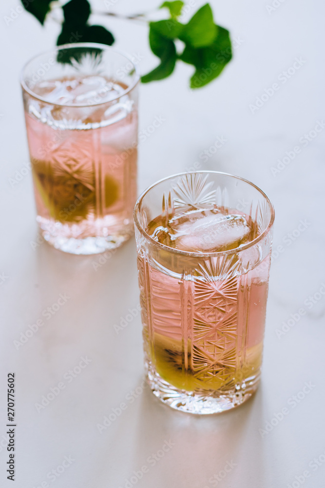 A glass of pink wine in a crystal glass on a marble background, green ivy and bright sun A glass of pink wine in a crystal glass on a marble background, green ivy and bright sun