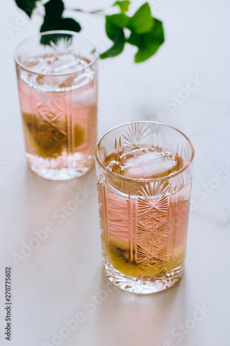 A glass of pink wine in a crystal glass on a marble background, green ivy and bright sun