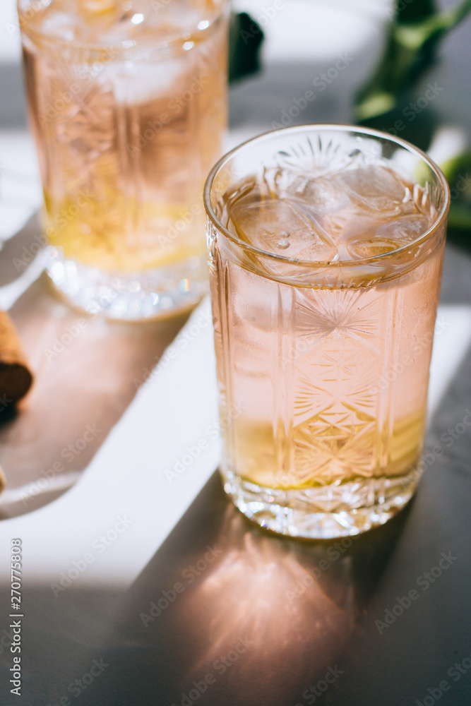 A glass of pink wine in a crystal glass on a marble background, green ivy and bright sun A glass of pink wine in a crystal glass on a marble background, green ivy and bright sun